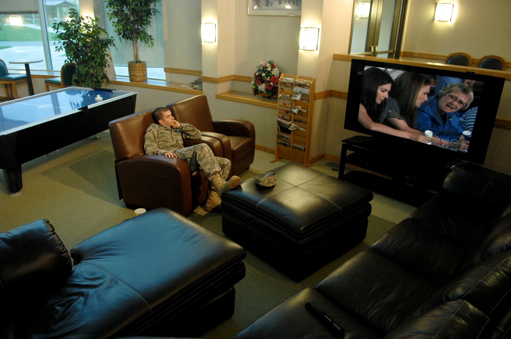 JOINT BASE ELMENDORF-RICHARDSON, Alaska -- Airman 1st Class Craig Weires, 673d Civil Engineer Squadron watches TV while sitting in brand new leather charis in Pollaris Hall's dayroom Aug. 10. Money from the 2010 Commander and Chief Installation Excellence award is being used in many different projects the most evident to Airmen is the upgrade of furnishings in dormitory day rooms. (Air Force photo by Airman 1st Class Jack Sanders)