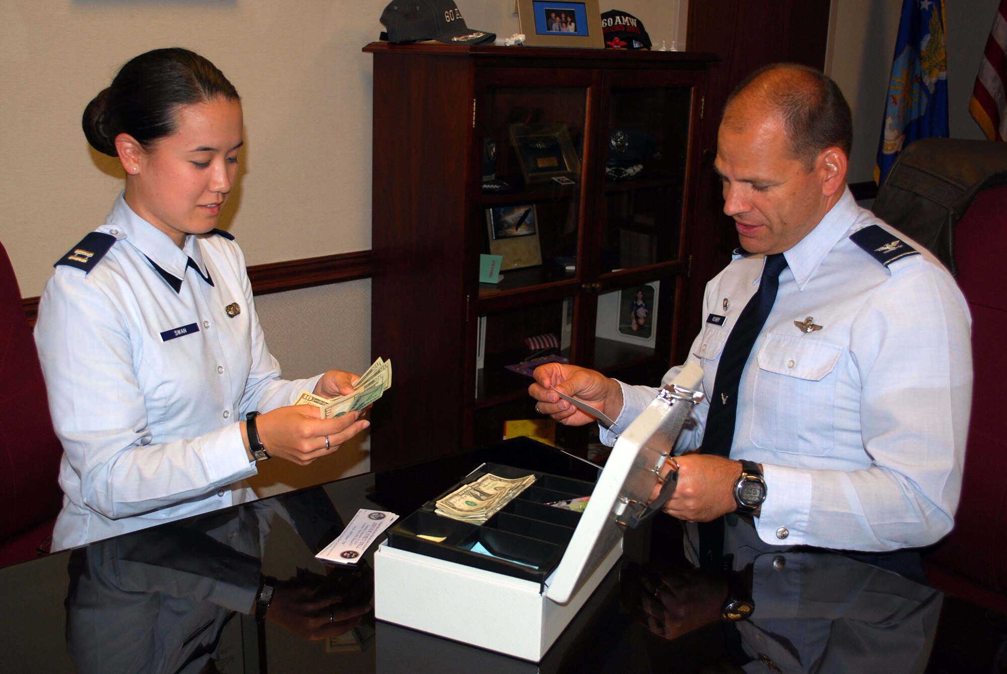 Col. James Vechery, 60th Air Mobility Wing commander, buys his tickets to the Air force Ball from Capt. Vanessa Swan, 60th Air Mobility protocol chief. The Air Force Ball is an event scheduled Sept. 18 that celebrates the birth of the Air Force. (U.S. Air Force photo/ Capt. Melissa Milner)