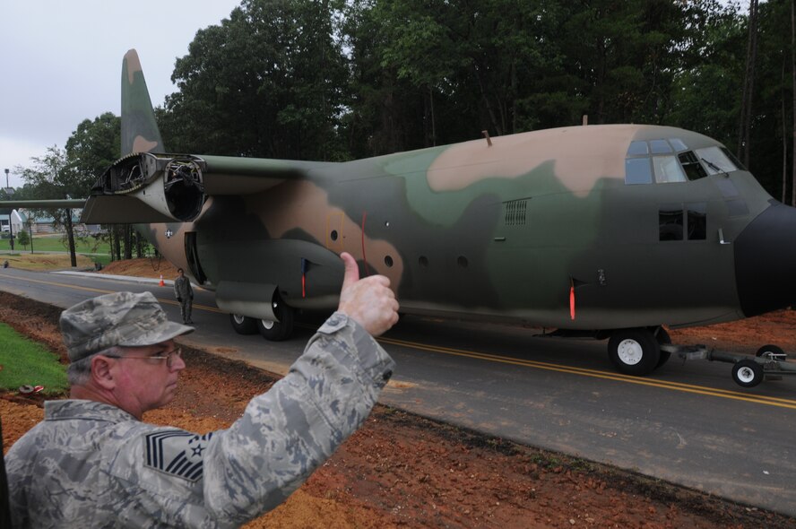 Charlotte, NC. Chief Master Sgt. Greg Trantham gives the signal for all clear before a wingless C-130 “B” Hercules cargo plane is towed to a corner of the base, to become a static display at the 145th Airlft Wing,  North Carolina Air National Guard base in Charlotte. One placed into position, the airplane will be visible from Billy Graham Parkway. Photo by Tech. Sgt. Brian E. Christiansen, North Carolina Air National Guard.