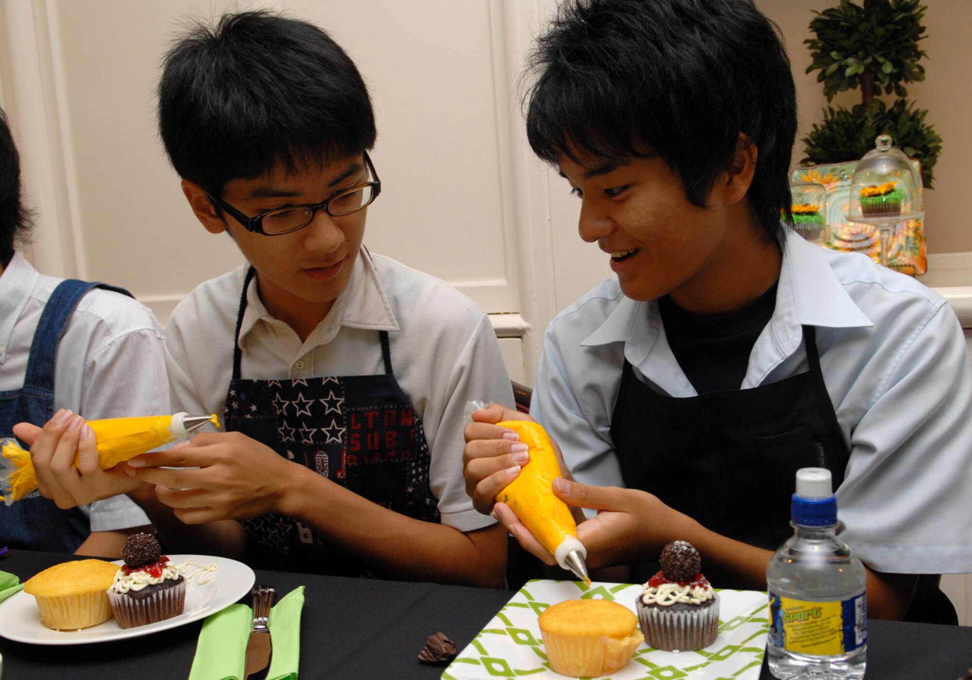 Kenta Kuniyoshi and Takumi Miyazato participate in a cupcake decorating lesson provided by Mrs. Cindy Wilsbach, wife of Brig. Gen. Ken Wilsbach, 18th Wing commander, at Kadena Air Base, Aug. 18. Students from the Junior and Senior High School Affiliated to Showa Pharmaceutical University attended the event in the Wilsbach’s home. (U.S. Air Force Photo/Junko Kinjo)