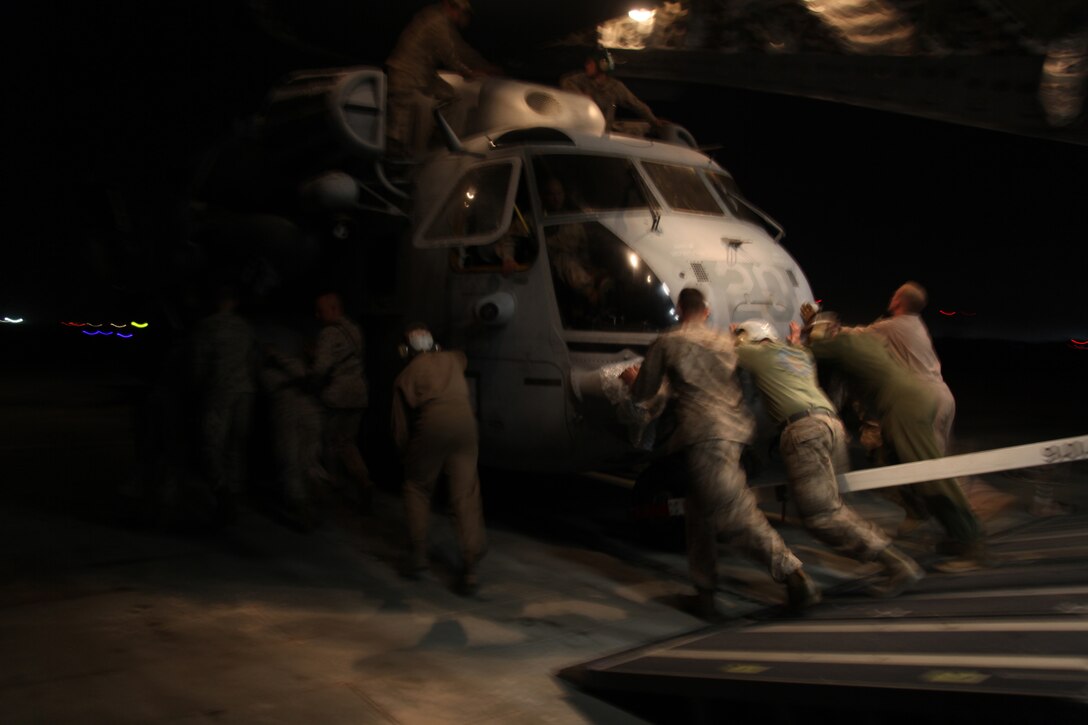 Marines from Marine Heavy Helicopter Squadron 361, 3rd Marine Aircraft Wing (Forward) and Marine Medium Tiltrotor Squadron 266 (Reinforced), 26th Marine Expeditionary Unit, work together to push a CH-53E Super Stallion off an Air Force C-17 Globemaster III cargo plane Aug. 22.  HMH-361 will share a workspace with VMM-266 (Rein) during the squadron's build up of four Super Stallions.  3rd MAW (Fwd) is simultaneously supporting combat operations and aiding the 26th MEU in their preparation for humanitarian relief efforts in Pakistan.