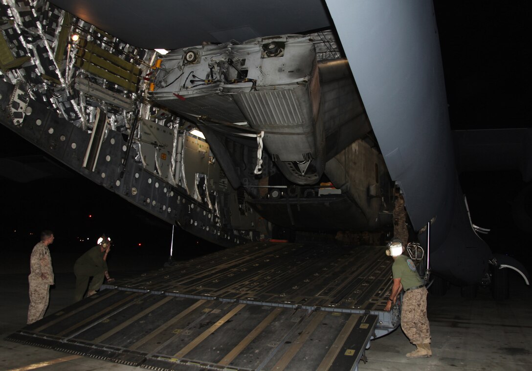 Marines from Marine Heavy Helicopter Squadron 361, 3rd Marine Aircraft Wing (Forward), watch as a CH-53E Super Stallion belonging to Marine Medium Tiltrotor Squadron 266 (Reinforced), 26th Marine Expeditionary Unit, is unloaded from an Air Force C-17 Globemaster III cargo plane Aug. 22. HMH-361 Marines were on site to aid the detachment with the unloading and transport of the disassembled Super Stallion. 3rd MAW (Fwd) is providing site support to the detachment as they make their way to aid in the Pakistan relief efforts.
