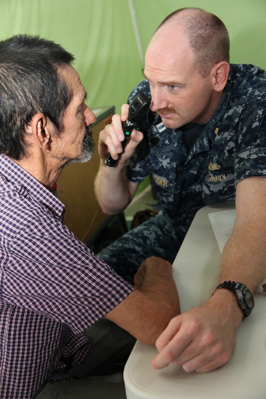 Navy Lt. Brian D. Engesser, an optometrist from Marine Corps Base Camp Lejeune, N.C., attached to Continuing Promise 2010, checks a Costa Rican manâ??s eyes before giving him reading glasses at a medical site in a high school gymnasium in Bribri, Costa Rica, Aug. 23, 2010, during CP10. Marines, sailors and USS Iwo Jima personnel are ported in Limon, Costa Rica, providing medical, dental, veterinary, community relations and engineering services to Costa Ricans as part of the CP10 mission during their deployment to the Caribbean, Central and South America.