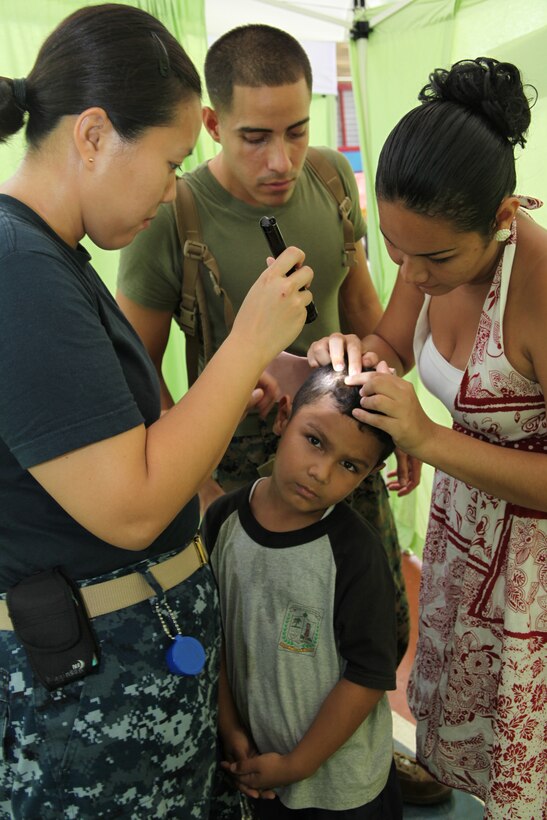 Navy Lt. Amber Higginson, a medical officer from Bethesda, Md., and Lance Cpl. Reinaldo Reyes, native of Yabucoa, Puerto Rico, and Spanish translator from Company A, 2nd Assault Amphibian Battalion, Ground Combat Element of Special-Purpose Marine Air Ground Task Force Continuing Promise 2010, check a child for skin rashes at a medical site in a high school gymnasium in Bribri, Costa Rica, Aug. 23, 2010. Marines, sailors and USS Iwo Jima personnel are ported in Limon, Costa Rica, providing medical, dental, veterinary, community relations and engineering services to Costa Ricans as part of the CP10 mission during their deployment to the Caribbean, Central and South America.