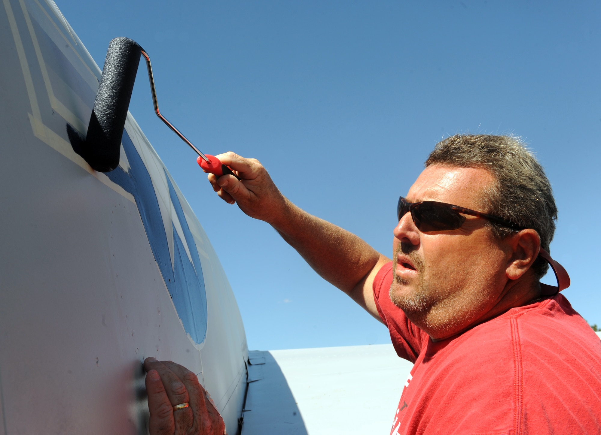 MOUNTAIN HOME AIR FORCE BASE, Idaho – Robby Tatum paints an emblem on a static F-100 in Holt Park Aug 12. The static displays are under a five-year-painting contract.  This year, the F-16 Fighting Falcon, F-100 Super Sabre and F-86 Sabre are being repainted. (U.S. Air Force photo by Airman 1st Class Debbie Lockhart)