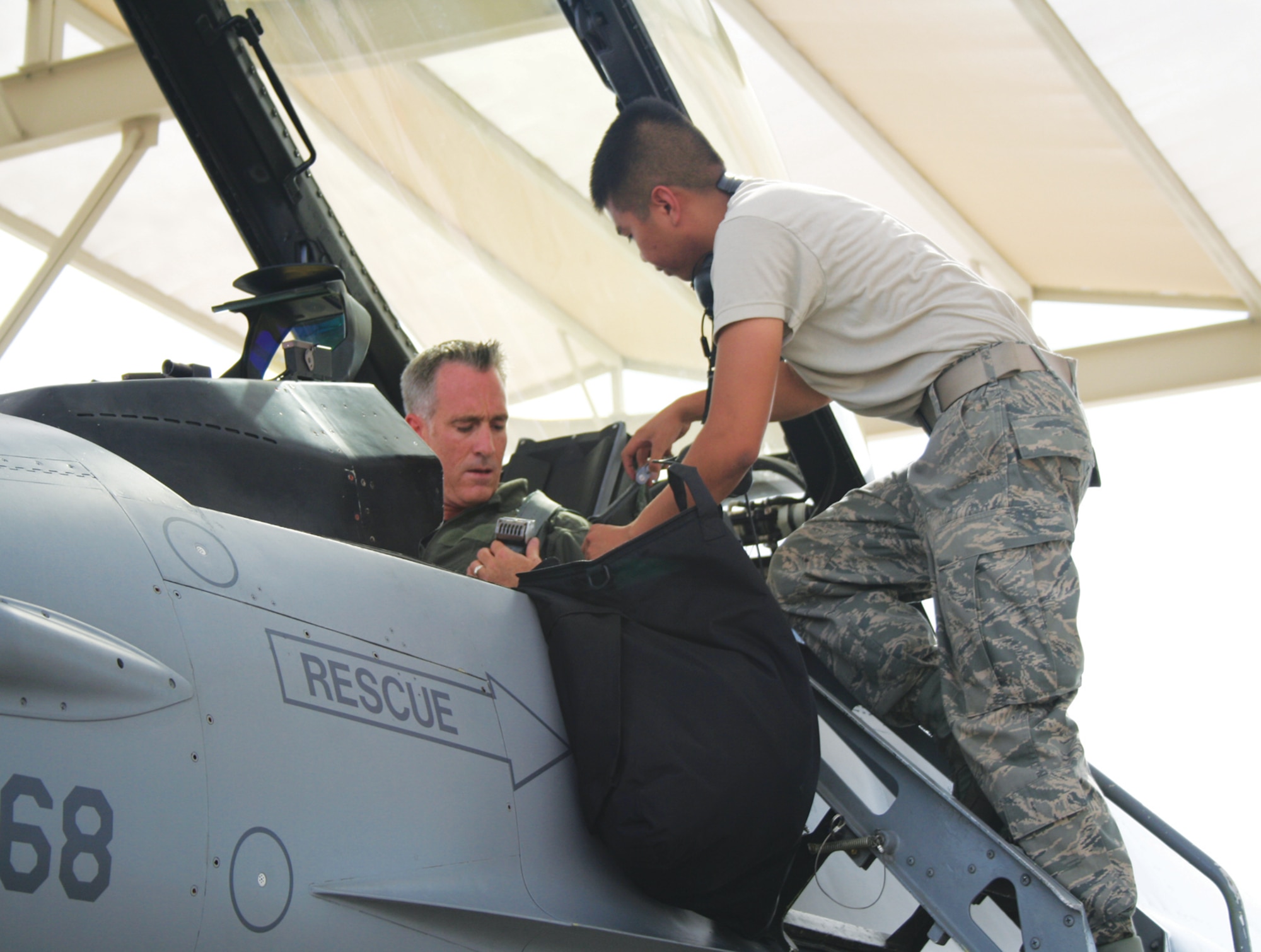 A student in the Mission Ready Airman course at Luke Air Force Base, Arizona, straps-in an F-16 Fighting Falcon pilot during hands-on training.  MRA has graduated more than 9,000 students since opening in 1994.  (U.S. Air Force photo/Staff Sgt. Heather Dolar)