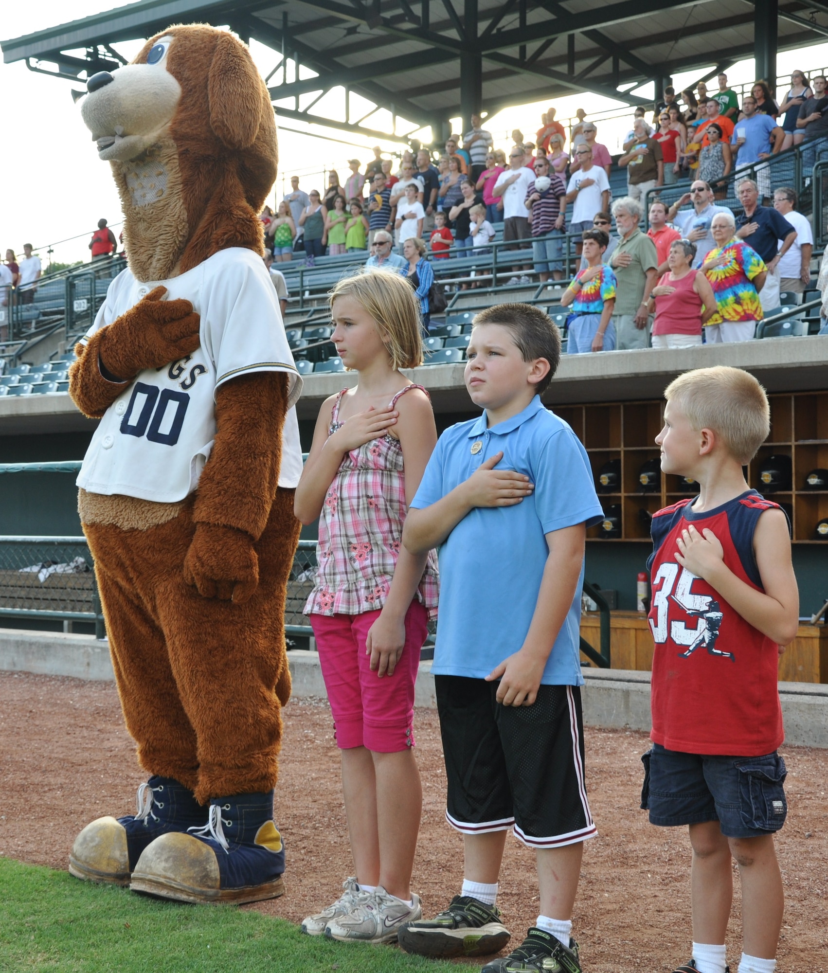 Children attending the military appreciation night opening ceremony stand with the RiverDogs mascot during the singing of the national anthem Aug 19, 2010 at Joseph P. Riley, Jr. Park in Charleston, S.C. (U.S. Air Force photo/Staff Sgt. Shane Ellis)