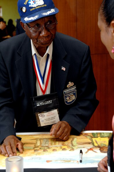 Original Tuskegee Airman Buford A. Johnson signs a poster for a woman during the Tuskegee Airmen, Inc. Convention, San Antonio, Texas. TAI is a non-profit organization dedicated to honoring the accomplishments of African-Americans who participated in air and ground crew as well as operations support in the Army Corps during World War ll. Retired Master Sergeant Buford was featured in The Beacon
in April, following his speaking engagement with more than 700 federal employees in Laguna Niguel, Calif. The Riverside chapter of the Tuskegee Airmen is named after Johnson and meets monthly at the March Field Museum. (U.S. Air Force photo by Staff Sgt. Joseph Araiza)
