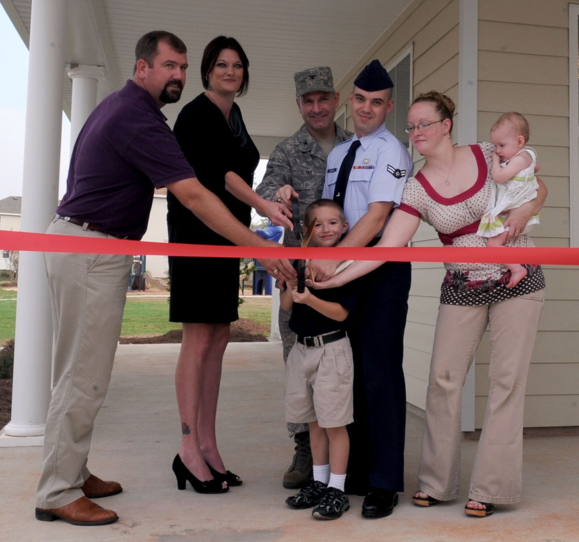 BARKSDALE AIR FORCE BASE, La. - (From left to right) Matt Hoel, Hunt project manager, Elizabeth Kirkpatrick, Pinnacle investor and Col. Timothy Fay, 2d Bomb Wing commander assist the Boston family, Airman 1st class Gary and Helena, children Gary Jr., 6 and Annie, 11months, wtih the ribbon cutting of their newly three bedroom duplex home Aug. 18.The Boston family is one of 97 families to move into the Liberty Heights housing area. (U.S. Air Force photo by Senior Airman La'Shanette V. Garrett) (RELEASED)