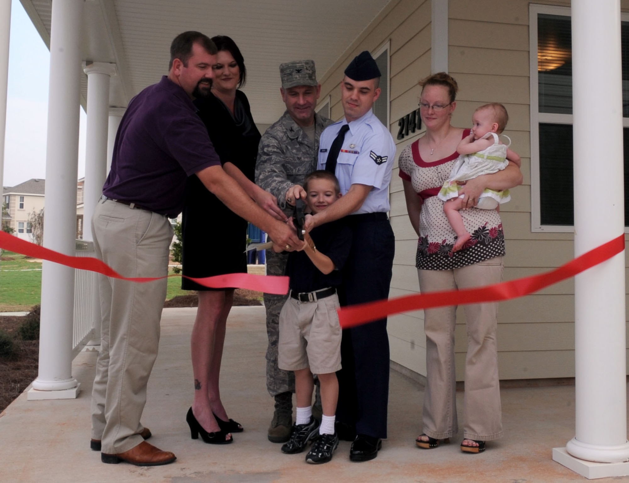 BARKSDALE AIR FORCE BASE, La. --  (From left to right) Matt Hoel, Hunt project manager, Elizabeth Kirkpatrick, Pinnacle investor and Col. Timothy Fay, 2d Bomb Wing commander assist the Boston family, Airman 1st class Gary and Helena, children Gary Jr., 6 and Annie, 11months, wtih the ribbon cutting of their newly three bedroom duplex home Aug. 18.The Boston family is one of 97 families to move into the Liberty Heights housing area. (U.S. Air Force photo by Senior Airman La'Shanette V. Garrett) (RELEASED)