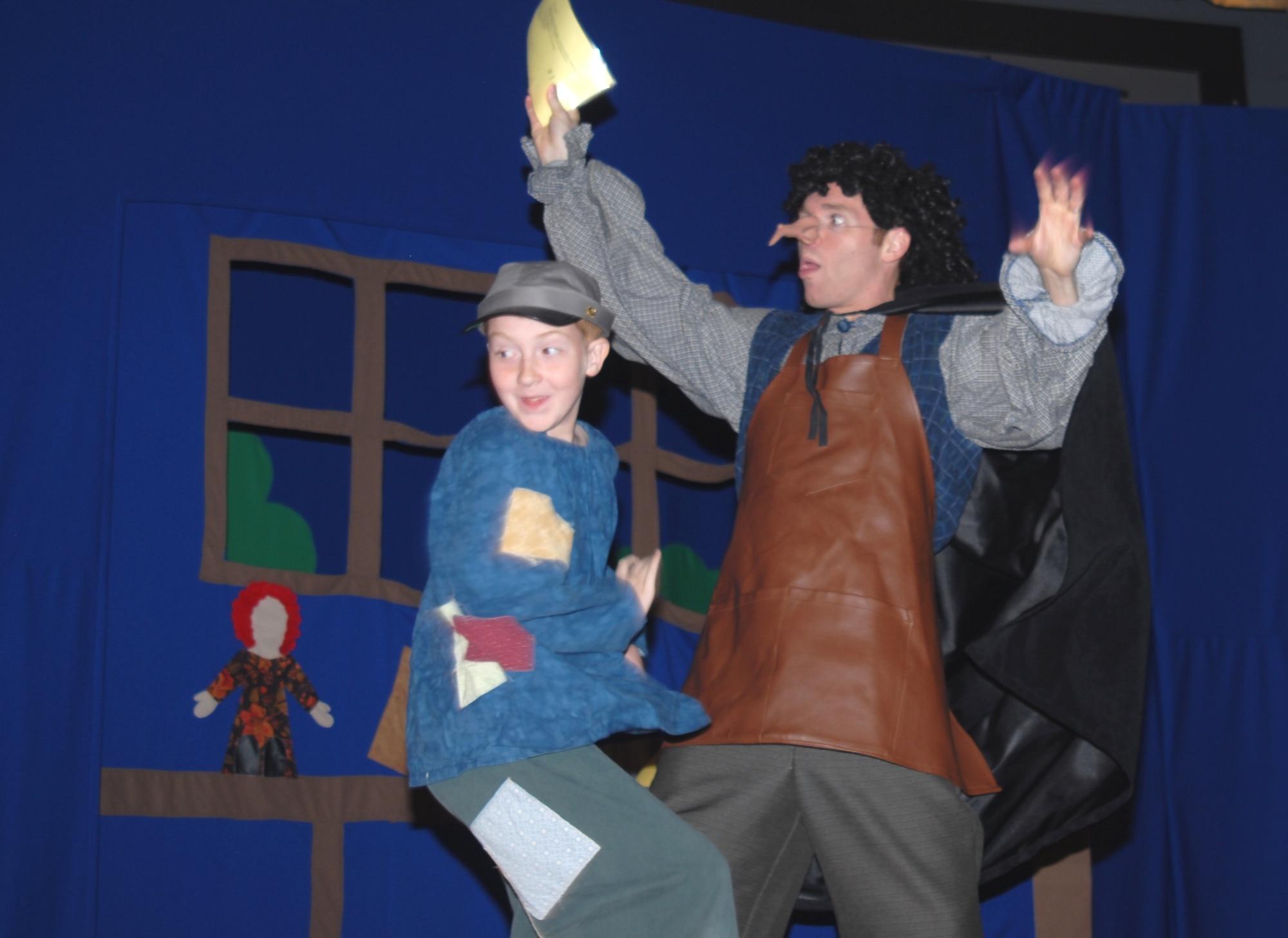 After delivering a telegram Urchin, Ben Ingalls, runs away before the angry Stromboli, Brian Epperson, can get him during this year's Missoula Children's Theatre Pinocchio play Aug. 21 at the base theater. Auditions for the show here were held at the beginning of the week casting 53 youths in grades K-12 into their roles. They rehearsed throughout the week, learning lines, songs and choreography in preparation for their two shows as an ensemble. (U.S. Air Force photo/Connie Hempel)