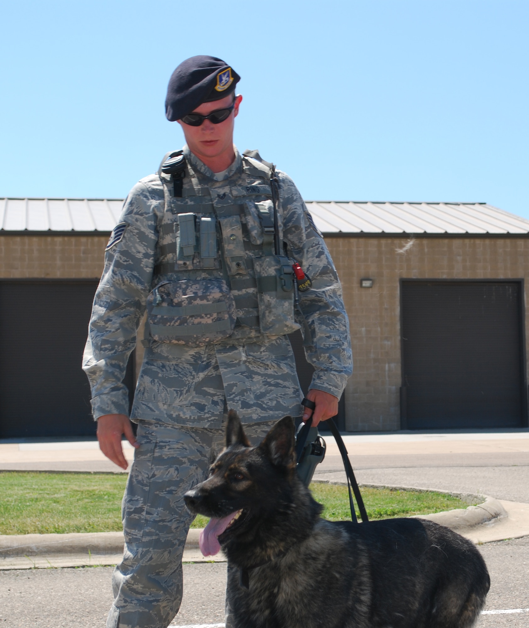 Staff Sergeant Adam Ring, 341st Security Forces Squadron member, takes a break from inspecting vehicles for an exercise with military working dog “Fritz” outside of building 300 July 28. (U.S. Air Force photo/Airman 1st Class Kristina Overton)