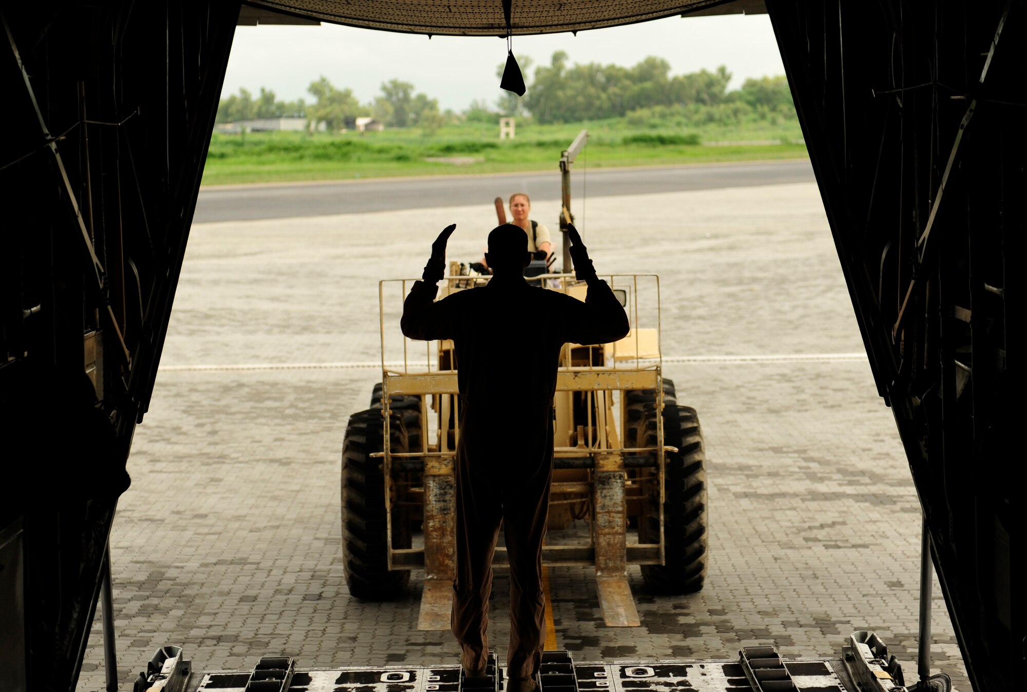 U.S. Air Force Master Sgt. John Metcalf a C-130H Hercules assigned to the 746th Expeditionary Airlift Squadron, signals in fork lift for cargo off load in Pakistan Aug. 20, 2010. The 746 EAS is staged out of Bagram Airfield, Afghanistan, running humanitarian relief missions to Pakistan. (U.S. Air Force photo by Staff Sgt. Andy M. Kin/Released)