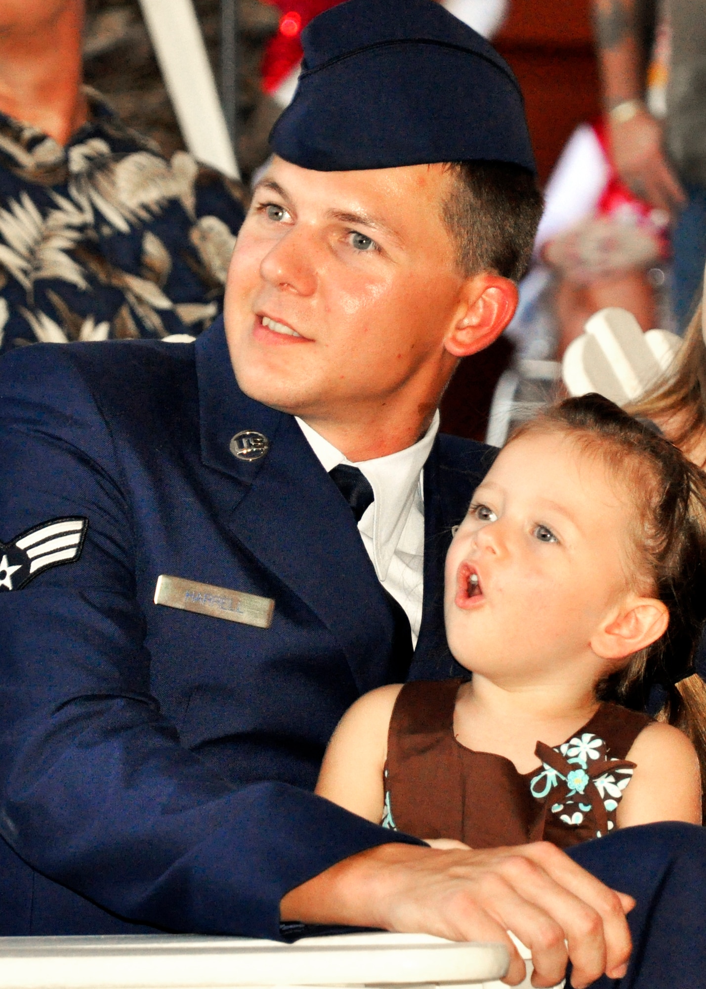 Senior Airman Brandon Harrell, 96th Civil Engineer Squadron explosive ordnance disposal journeyman, watches T-6 Texans fly overhead with his daughter, Hannah, at the Red, White and Blue Celebration Aug. 19. Airman Harrell was recognized as a local hero for his brave actions during a Taliban ambush while on patrol in Afghanistan in 2009. The hero also made the staff sergeant promotion list the same day. (U.S. Air Force Photo/Jasmine DeNamur)