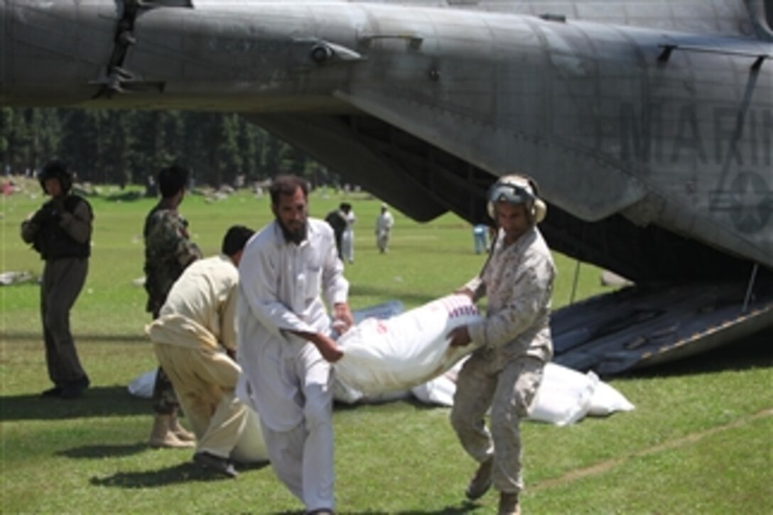 U.S. Marine Capt. Paul D. Duncan assists a Pakistani civilian unloading a U.S. Marine Corps CH-53E Super Stallion helicopter during humanitarian relief efforts in Khyber-Pakhtunkhwa province, Pakistan, on Aug. 18, 2010.  