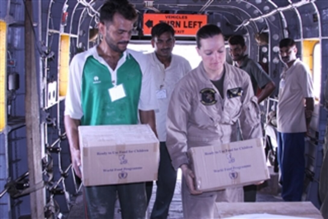 U.S. Marine Corps Sgt. Jill Wells (2nd from right), with Marine Medium Helicopter Squadron 165 (Reinforced), 15th Marine Expeditionary Unit, helps Pakistani men load food into a Marine Corps CH-53E Super Stallion helicopter during a humanitarian mission in Khyber Pakhtunkhwa province, Pakistan, on Aug. 13, 2010.  