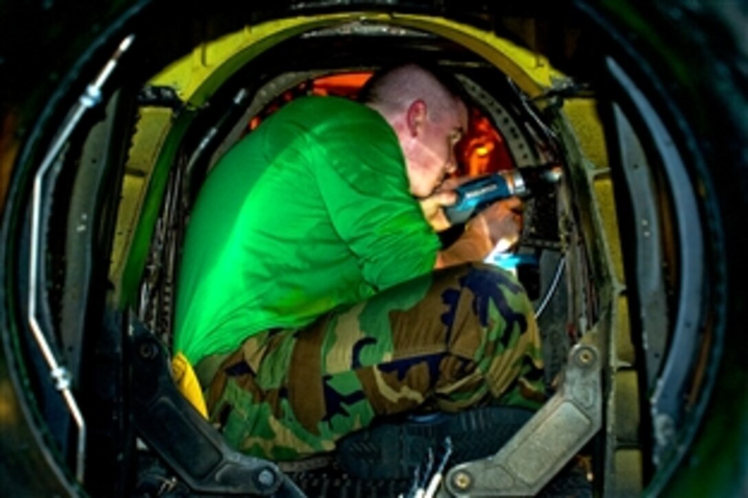 U.S. Navy Petty Officer 3rd Class James Brisendine drills out corroded anchor nuts to repair an access cover on the engine nacelle of an E-2C Hawkeye aircraft in the hangar bay of the USS George Washington in the Pacific Ocean, Aug. 17, 2010. 