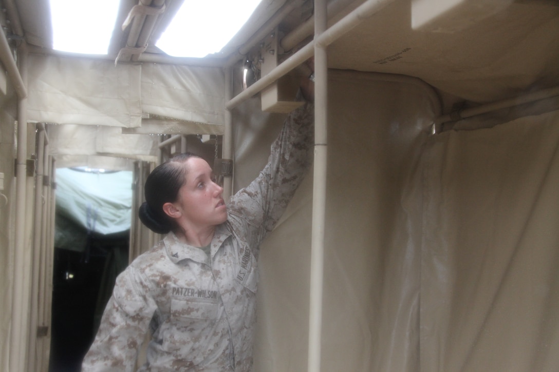 Lance Cpl. Amanda L. Patzer-Wilson demonstrates how she and her fellow Marines set up showers with working hot water during the Marine Wing Communications Squadron 28 field training exercise at Marine Corps Outlying Field Camp Davis, N.C., Aug. 24. Patzer-Wilson is a basic electrician with Engineer Company, Marine Wing Support Squadron 271.