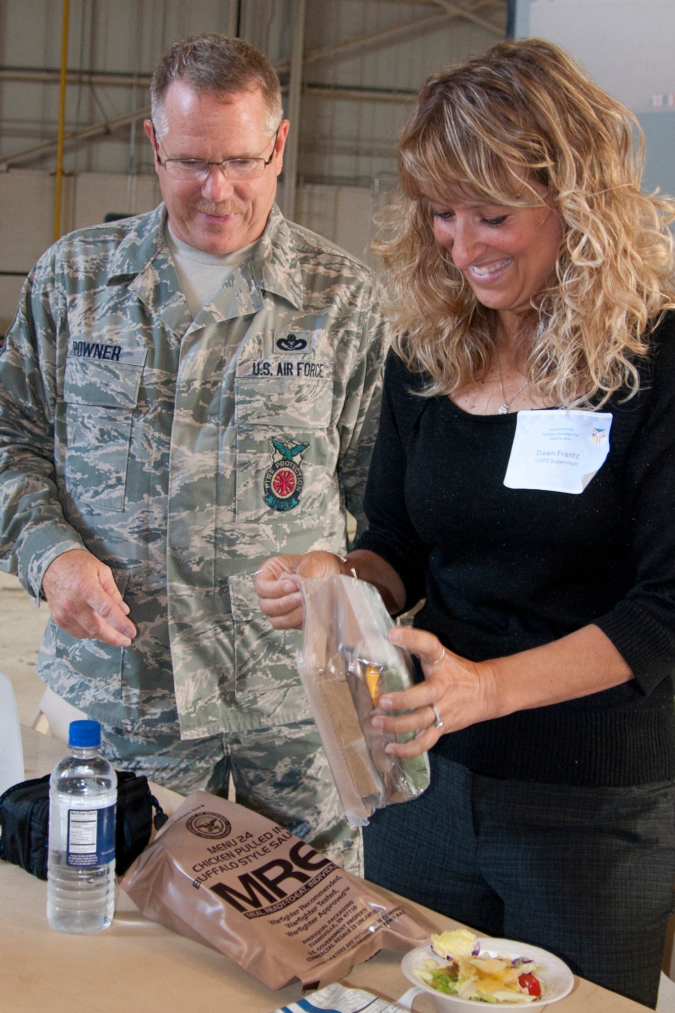 YOUNGSTOWN AIR RESERVE STATION, Ohio--U.S. Air Force Reserve Chief Master Sgt. Thomas J. Powner, 910th Civil Engineer Fire Department chief, assists USPS supervisor, Dawn Frantz, prepare a Meal Ready to Eat Aug. 8 during the 910th Airlift Wing's annual Employer Awareness Day. Ms. Frantz was among 60 employers nominated by wing Reservists to recognize them for aiding the Air Force???s mission.  U.S. Air Force Photo by Maj. Brent J. Davis.