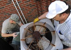 Craig Collins holds the condenser fan while U.S. Air Force Airman Codye Miller reconnects electrical wires Aug. 18, 2010, on Joint Base Charleston, S.C. Once all repairs are complete, technicians reassemble the unit, allow coolant to charge back to full capacity and run a test to ensure the job was a success. Airman Miller and Mr. Collins are heating, ventilation and air conditioning technicians with the 628th Civil Engineer Squadron. (U.S. Air Force photo/Senior Airman Timothy Taylor)