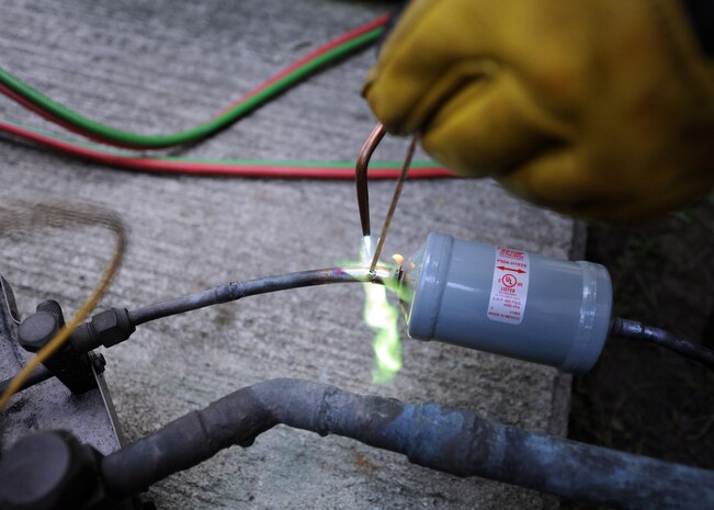 Craig Collins brazes a filter drier into place using an acetylene torch Aug. 18, 2010, on Joint Base Charleston, S.C. Filter driers help eliminate moisture, acids and debris from the cooling system. Mr. Collins is a heating, ventilation and air conditioning technician with the 628th Civil Engineer Squadron. (U.S. Air Force photo/Senior Airman Timothy Taylor)