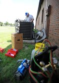 U.S. Air Force Airman Codye Miller and Craig Collins detach a damaged compressor to make room for a new one Aug. 18, 2010, on Joint Base Charleston, S.C. The compressor aids in transferring vaporized coolant to a liquid form. The compressed vapor is cooled via heat exchange with the outside air, wherein the vapor condenses to a fluid. Airman Miller and Mr. Collins are heating, ventilation and air conditioning technicians with the 628th Civil Engineer Squadron. (U.S. Air Force photo/Senior Airman Timothy Taylor)
