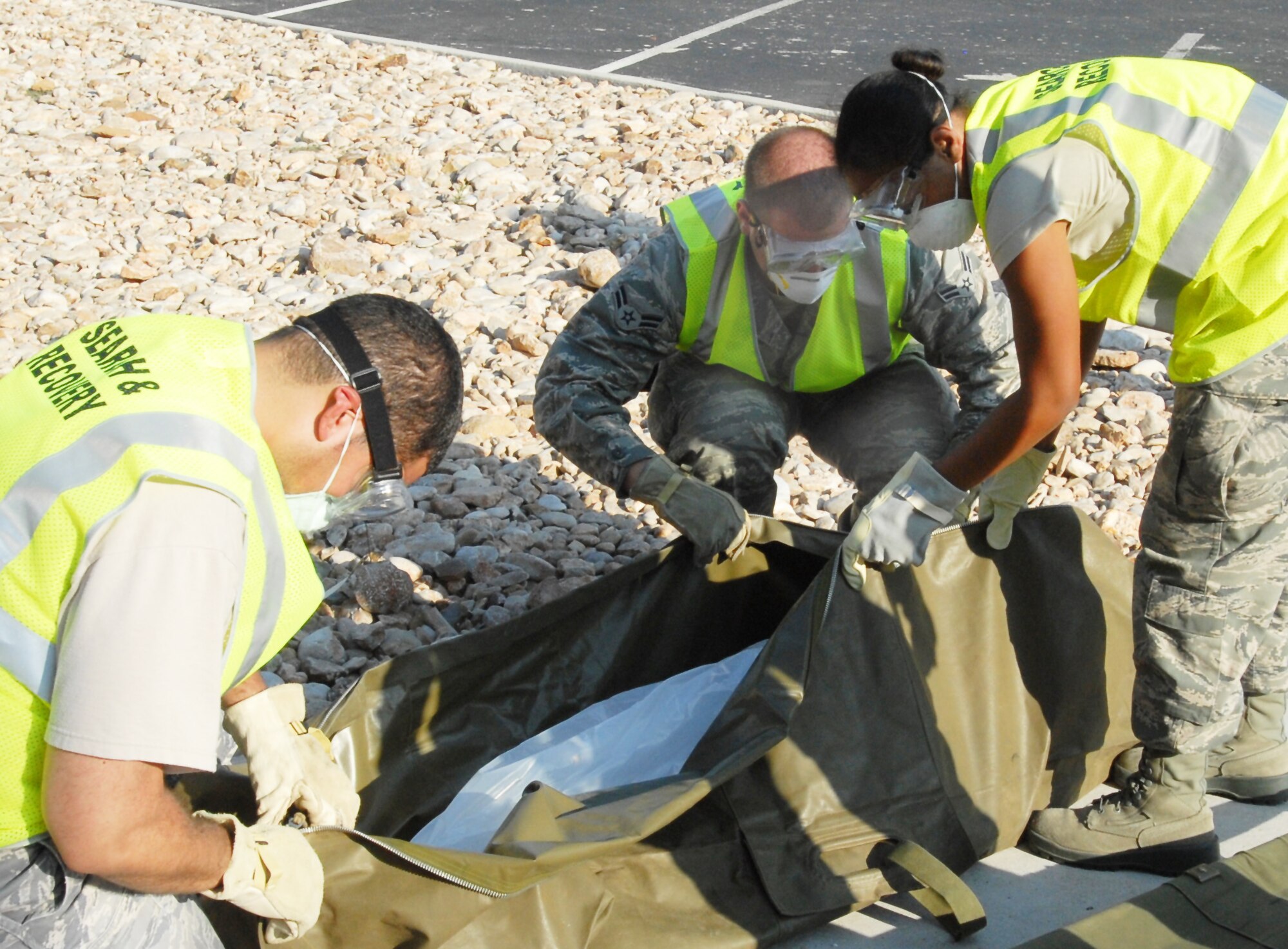 From left: Search and Recovery team members Staff Sgt. Michael Marrero, 17th Medical Group, Airman 1st Class Marcus Moss, 17th Communications Squadron, and Airman 1st Class Morgan Williams, 17th Force Support Squadron, prepare to lift one of the casualties outside Carswell Field House during the active shooter exercise Aug. 19. (U.S. Air Force photo/Lou Czarnecki)