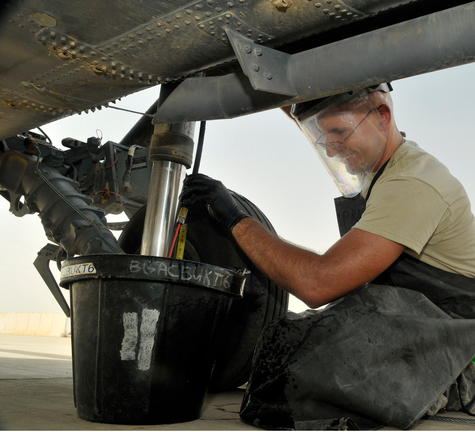 Staff Sgt. Michael Burch, 332nd Expeditionary Aircraft Maintenance Squadron 64th Expeditionary Helicopter Maintenance Unit crew chief, services the right-main landing gear strut on a HH-60 Pave Hawk helicopter Aug. 12, 2010, Joint Base Balad, Iraq. The struts are over filled with hydraulic fluid to ensure that the nose of the aircraft does not hit the load ramp of the C-17 Globemaster III cargo aircraft while unloading. Sergeant Burch, a native of Black, Ala., is deployed from Nellis Air Force Base, Nev. (U.S. Air Force photo/Staff Sgt. Phillip Butterfield)