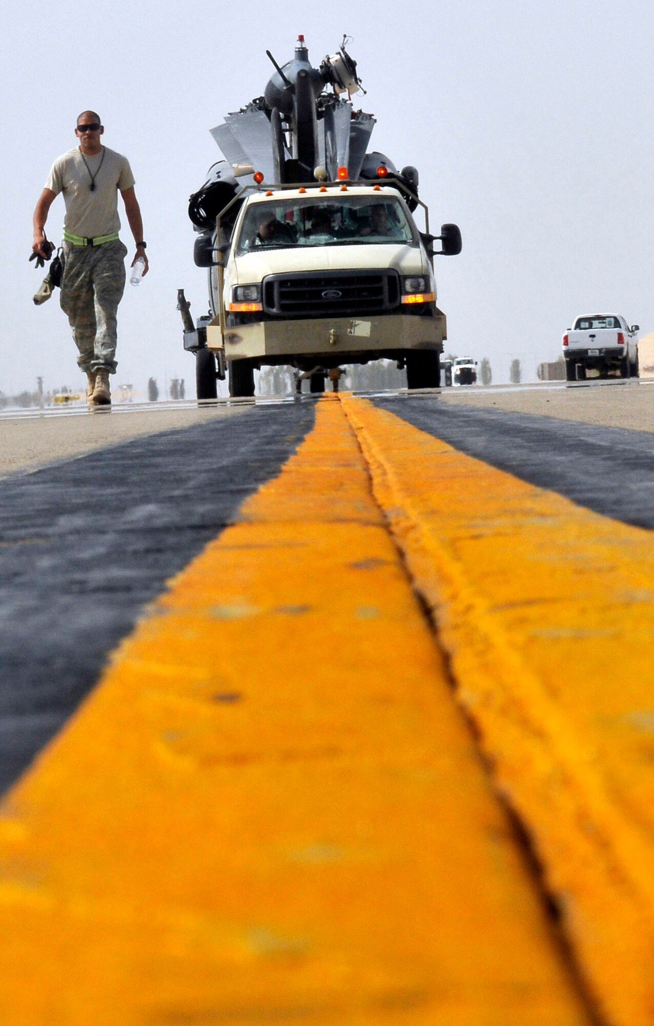 Staff Sergeant Eric Clayborn, 332nd Expeditionary Aircraft Maintenance Squadron, 64th Expeditionary Helicopter Maintenance Unit fuels technician, walks back to the lead vehicle after confirming the safety of the helicopter being towed Aug. 12, 2010, Joint Base Balad, Iraq. The 22,000-pound aircraft is towed at five mph, which is well suited for the unit’s low-geared Bobtail tow vehicle. Sergeant Clayborn is a native of Colorado Springs, Colo., deployed from Nellis Air Force Base, Nev. (U.S. Air Force photo/Staff Sgt. Phillip Butterfield) 