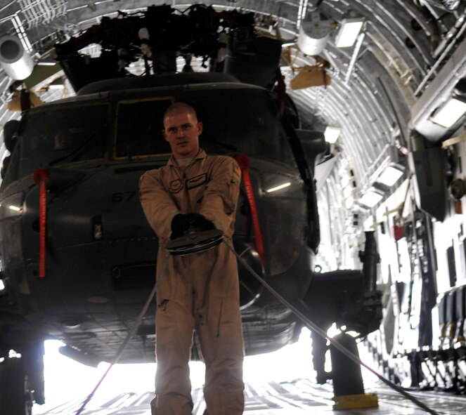 Airman 1st Class Brain Whitcomb, 816th Expeditionary Airlift Squadron loadmaster, pulls cable from the C-17’s deck pulley system to attach to a HH-60 Pave Hawk helicopter during a mission to Joint Base Balad, Iraq, on Aug. 12, 2010. Airman Whitcomb was deployed from the 8th Airlift Squadron at Joint Base Lewis-McChord, Wash. (U.S. Air Force Photo/Staff Sgt. Phillip Butterfield)