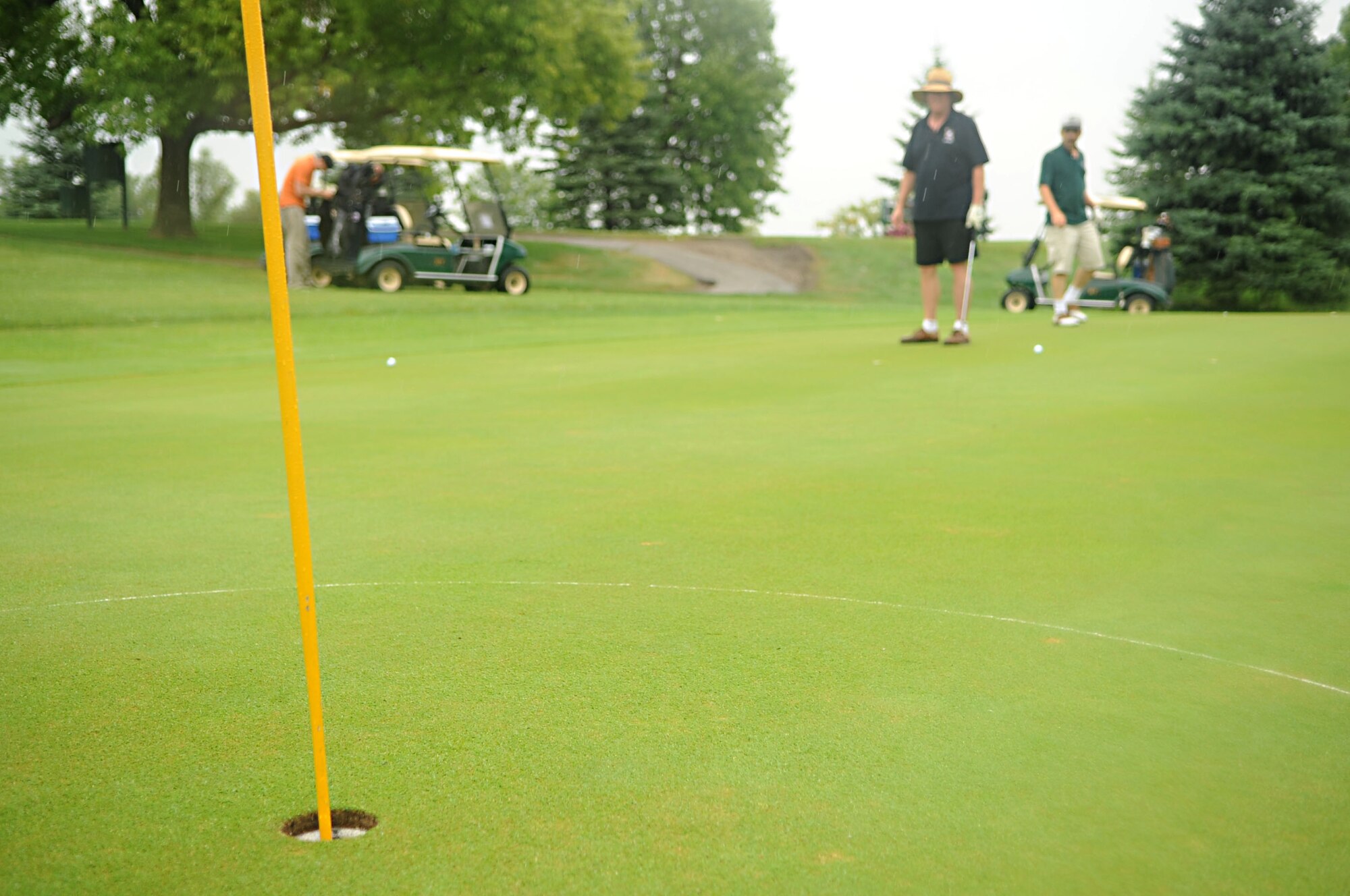 Chief Master Sgt. Ed Keller (middle), 319th Security Forces Squadron, looks at the hole to putt his golf ball into Aug. 23 during the Military Affairs Committee Golf Tournament at Grand Forks Country Club, N.D. The MAC Golf Tournament is an annual golf scramble consisting of two tournaments, one on Grand Forks AFB and one in the city of Grand Forks. Each four-man team is made up of both base personnel and members of the Grand Forks community. The event has been taking place since the 1980’s and continues to be a unique way for base and community members to interact. (U.S. Air Force photo by Senior Airman Amanda N. Stencil)