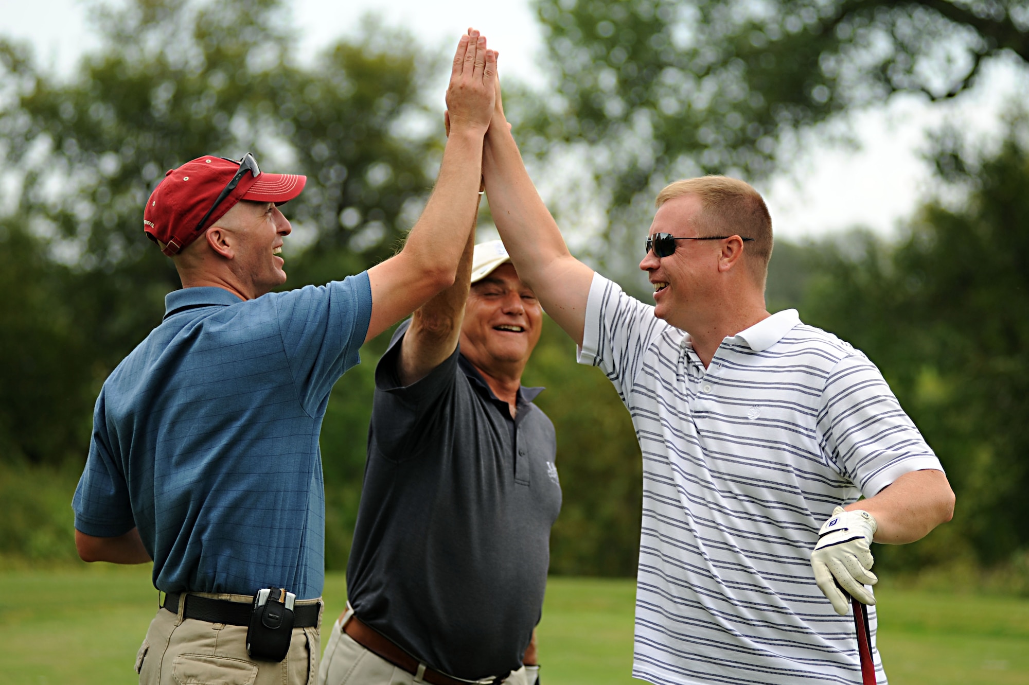 Lt. Col. Noel Bradford (left), 905th Air Refueling Squadron commander, Malcolm Rodacker (middle), and Master Sgt. Darin Mitchell (right), 319th Logistics Readiness Squadron, share a high five after teeing off Aug. 23 during the Military Affairs Committee Golf Tournament at Grand Forks Country Club, N.D. The MAC Golf Tournament is an annual golf scramble consisting of two tournaments, one on Grand Forks AFB and one in the city of Grand Forks. Each four-man team is made up of both base personnel and members of the Grand Forks community. The event has been taking place since the 1980’s and continues to be a unique way for base and community members to interact. (U.S. Air Force photo by Senior Airman Amanda N. Stencil)