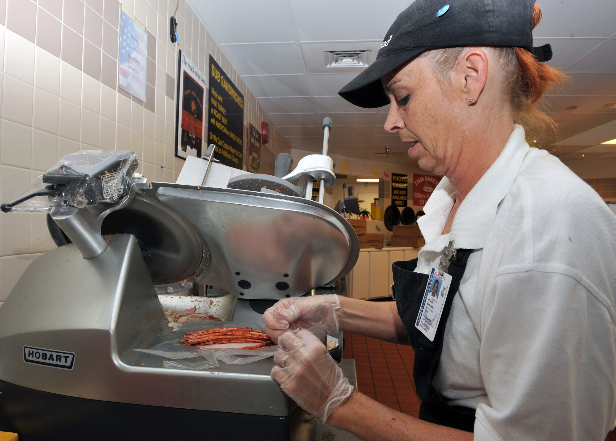 Meri Agnker, deli worker, custom slices an order for a customer Aug. 12 at the commissary deli. A variety of fresh-made sandwiches are offered daily by the deli department. (U.S. Air Force photo by Staff Sgt. Chris Willis)
