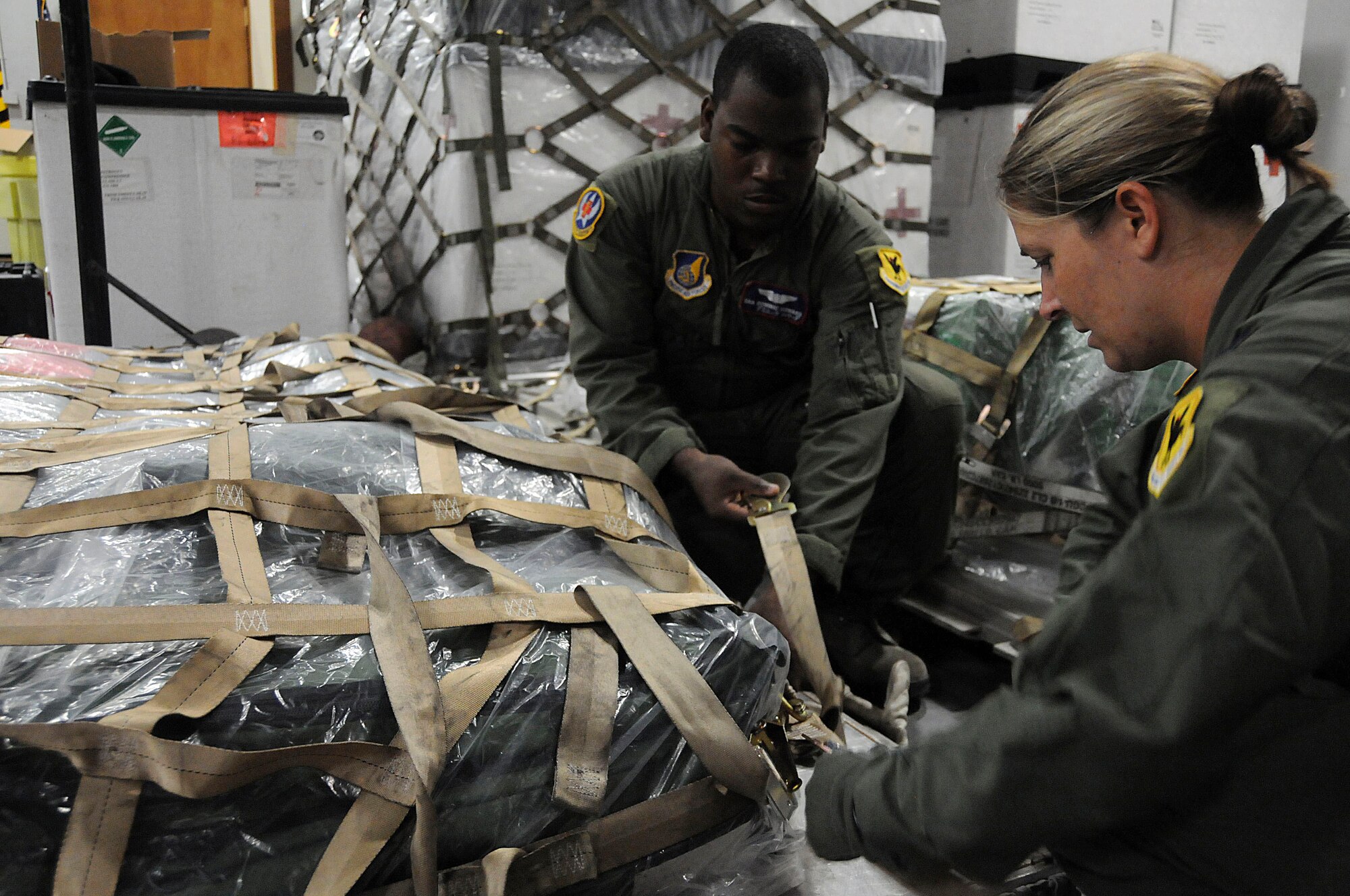 Senior Airman Dominc Howard, 18th Aeromedical Evacuation Squadron flight medical technician, and Capt. Catherine Jordan, 18th Aeromedical Evacuation Squadron flight nurse, tighten the top cargo net around a pallet during a Local Operational Readiness Exercise (LORE) at Kadena Air Base, Japan, Aug. 24, 2010. The LORE prepared Airmen for real-world contingency operations by simulating a wartime operational environment. (U.S. Air Force photo/Staff Sgt. Darnell T. Cannady)