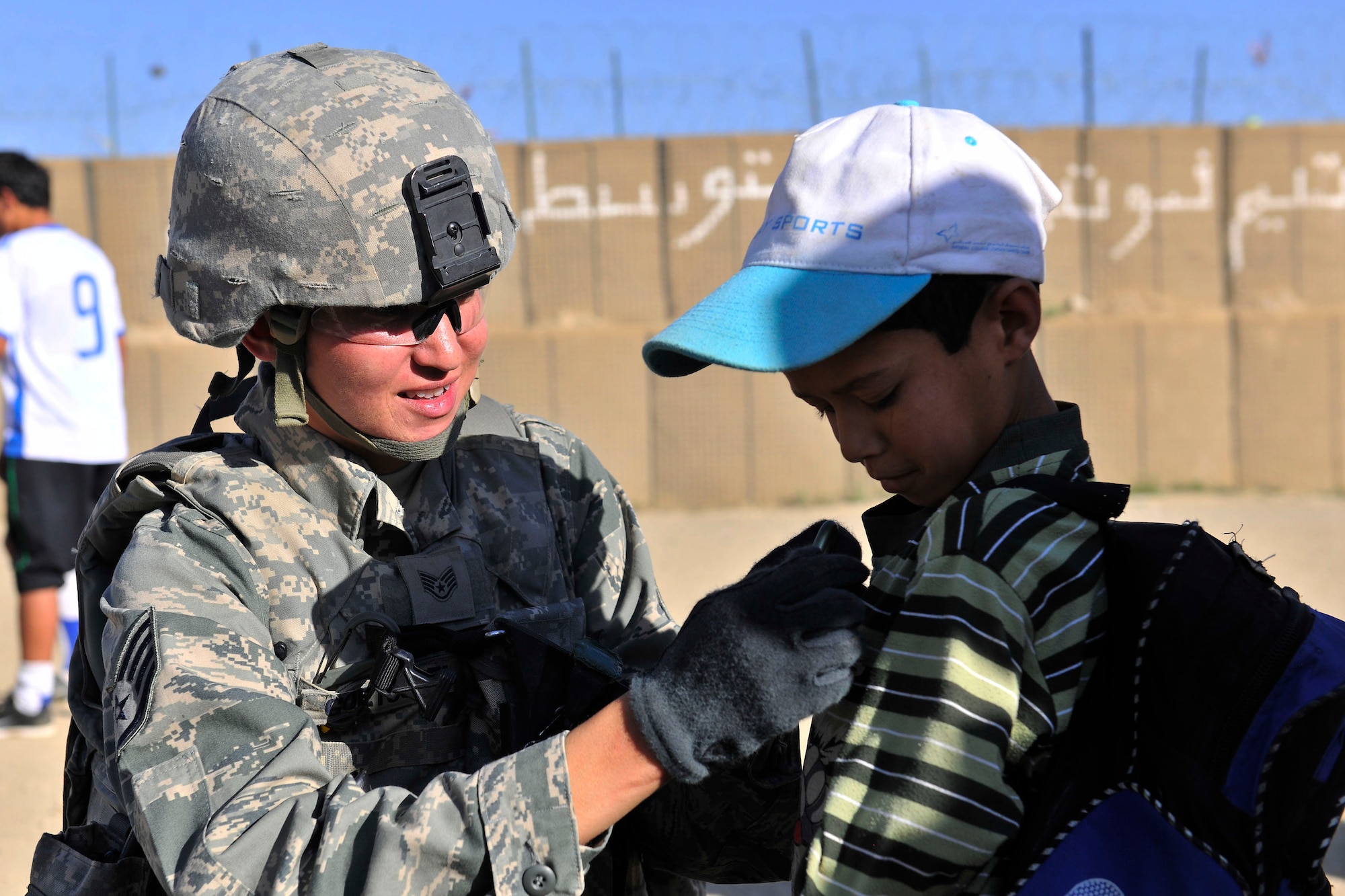 Staff Sgt. Alicia Goetschel, a 455th Expeditionary Security Forces member, attaches a carabiner to an Afghan boy outside of Bagram Airfield, Afghanistan, Aug. 22, 2010. The 455th ESFS compiled soccer equipment donated by the Future Business Leaders of America chapter at Desert Hills High School in Gilbert, Ariz., and distributed as part of a community strengthening program between the coalition forces and the Afghan people. (U.S. Air Force photo/Staff Sgt. Christopher Boitz)