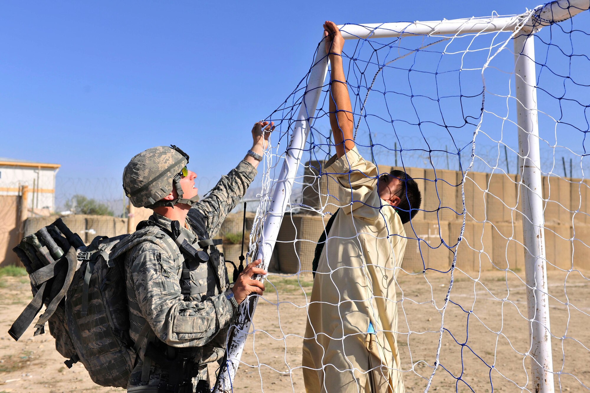 Senior Airman Lance Halverson, a 455th Expeditionary Security Forces Squadron member, and an Afghan youth set up a soccer net outside of Bagram Airfield, Afghanistan, Aug. 22, 2010. The 455th ESFS compiled soccer equipment donated by Future Business Leaders of America chapter at Desert Hills High School in Gilbert, Ariz., and distributed as part of a community strengthening program between the coalition forces and the Afghan people. (U.S. Air Force photo/Staff Sgt. Christopher Boitz)