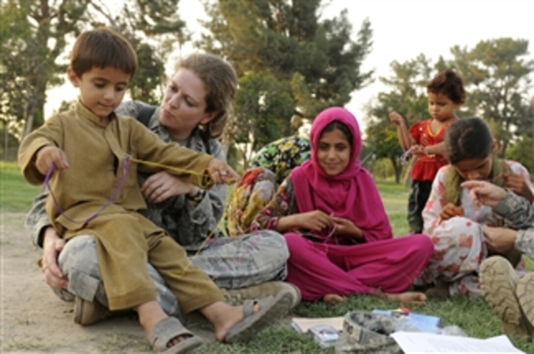 U.S. Air Force Capt. Mary Danner-Jones, a public affairs officer with the Nangarhar Provincial Reconstruction Team, teaches an Afghan boy and his sisters to make friendship bracelets during a Girl Scout meeting at Forward Operating Base Finley Shields in Jalalabad, Afghanistan, on Aug. 21, 2010.  