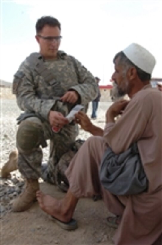A U.S. Army medic (left) attached to Legion Company, 1st Battalion, 503rd Infantry, 173rd Airborne Brigade Combat Team treats an Afghan flood victim and prescribes medicine at the Nerkh District Center near Combat Outpost Nerkh in Wardak province, Afghanistan, on Aug. 11, 2010.  