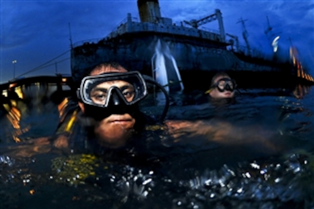 Peruvian Navy Diver Falcon Bernol, left, and U.S. Navy Petty Officer 1st Class Shawn Cooley, right, return to the pier after attaching salvage equipment to a sunken Panamanian navy patrol boat in Panama City, Panama, Aug. 19, 2010. U.S. sailors assigned to Mobile Diving and Salvage Unit 2, and teams from partner nations Panama, Columbia and Peru helped bring the boat to the surface after it was sunk by a tugboat's wake. 