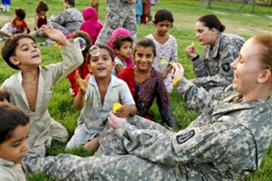 U.S. Army Sgt. Amber Anderson, foreground, and Spc. Jessica George, background, blow bubbles with Afghan children during a Girl Scouts meeting on Forward Operating Base Finley Shields in Jalalabad, Afghanistan, Aug. 21, 2010. Anderson, an explosive ordnance disposal team member, and George are assigned to the 101st Airborne Division's Special Troops Battalion.