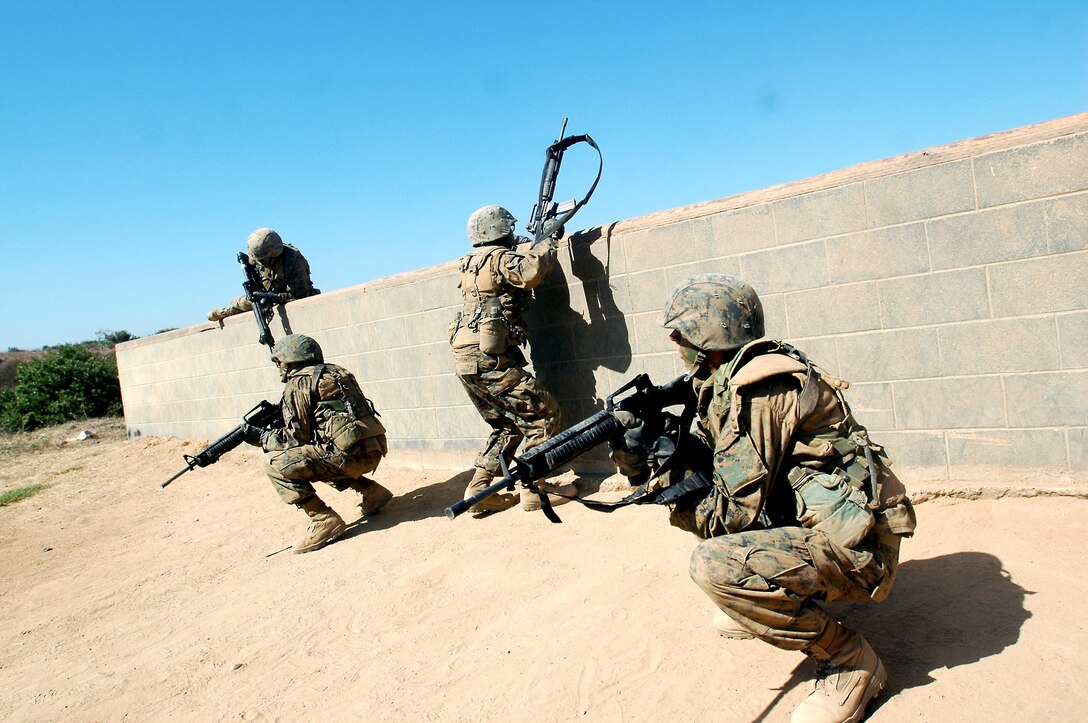 Recruits Robert Streety, left, and Derrick Knippel, right, provide cover for their fire team as they maintain a low profile and overcome a wall during their attack on simulated enemy positions during the Crucible, Aug. 24. During Copland’s Fire Team Assault Course, the recruits’ Armored Personnel Carrier undergoes a simulated attack consisting of an Improvised Explosive Device followed by an ambush of machine gun and mortar fire.