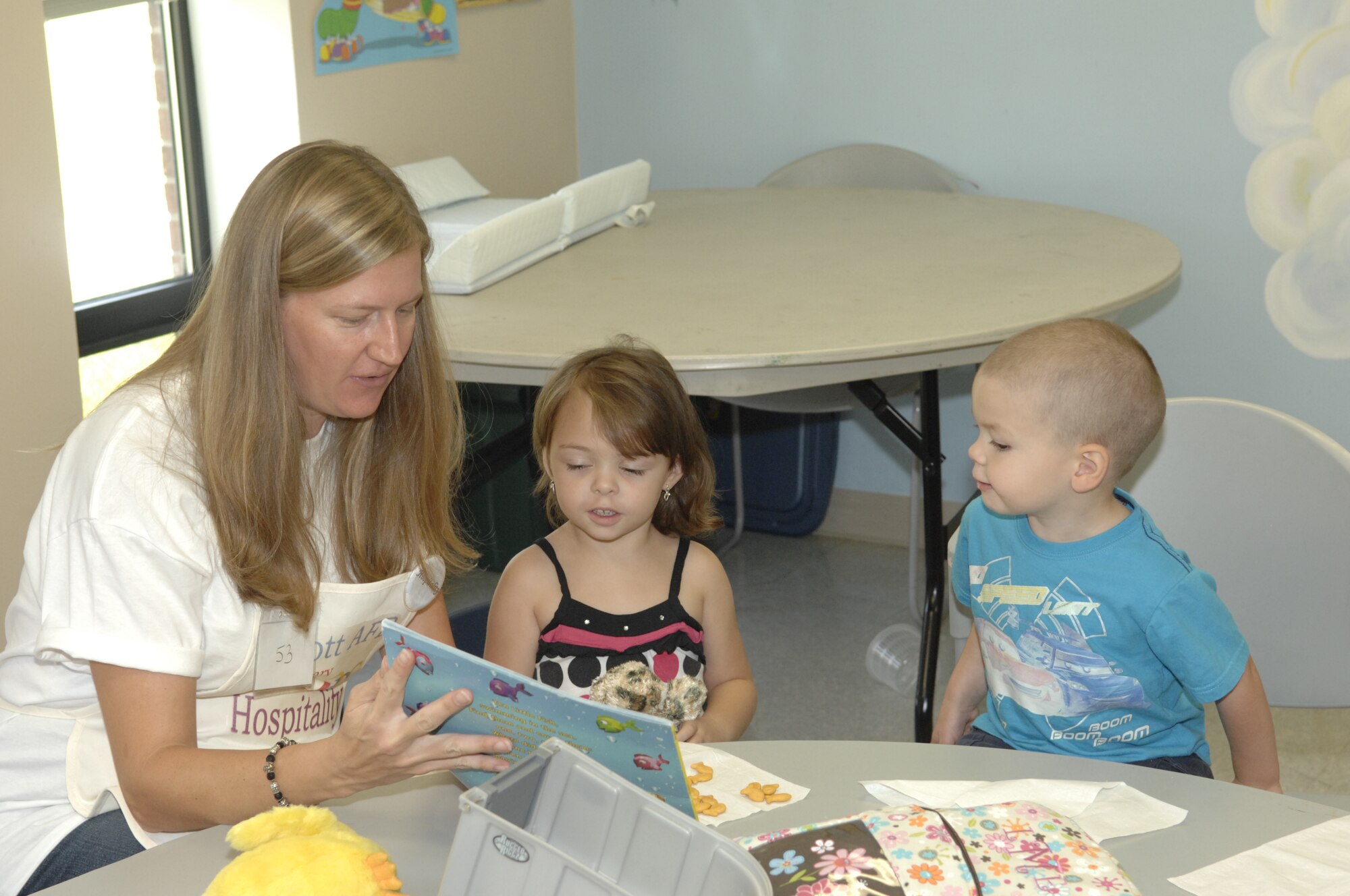 SCOTT AIR FORCE BASE, Ill. -- Samantha Meinders reads to Brianna Speck and Jack Fondren in the nursery while their mothers participate in Mothers of Pre-Schoolers or MOPS, a support and activity group for mothers of young children sponsored by the Chapel staff. MOPS meets the first and third Friday of every month at Chapel 1 and people can register anytime. (U.S. Air Force photo/ Airman 1st Class Amber R. Kelly-Herard