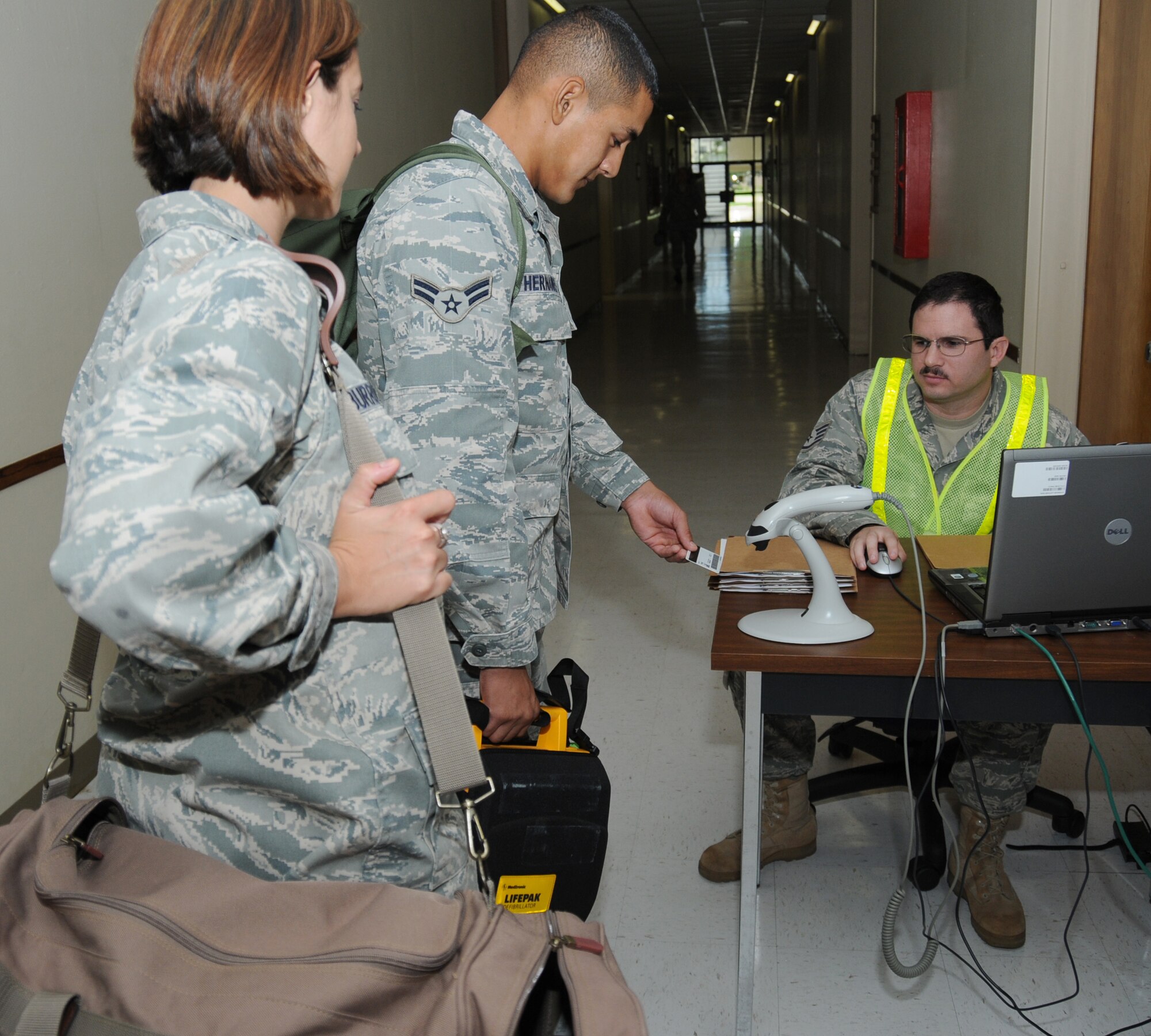 From left, Capt. Donna Burrowes and Airman Guillermo Hernandez, 81st Medical Operations Squadron, are checked into the Jones Hall shelter by Staff Sgt. Christopher Guertin, 338th Training Squadron shelter management team member.  (U.S. Air Force photo by Kemberly Groue)
