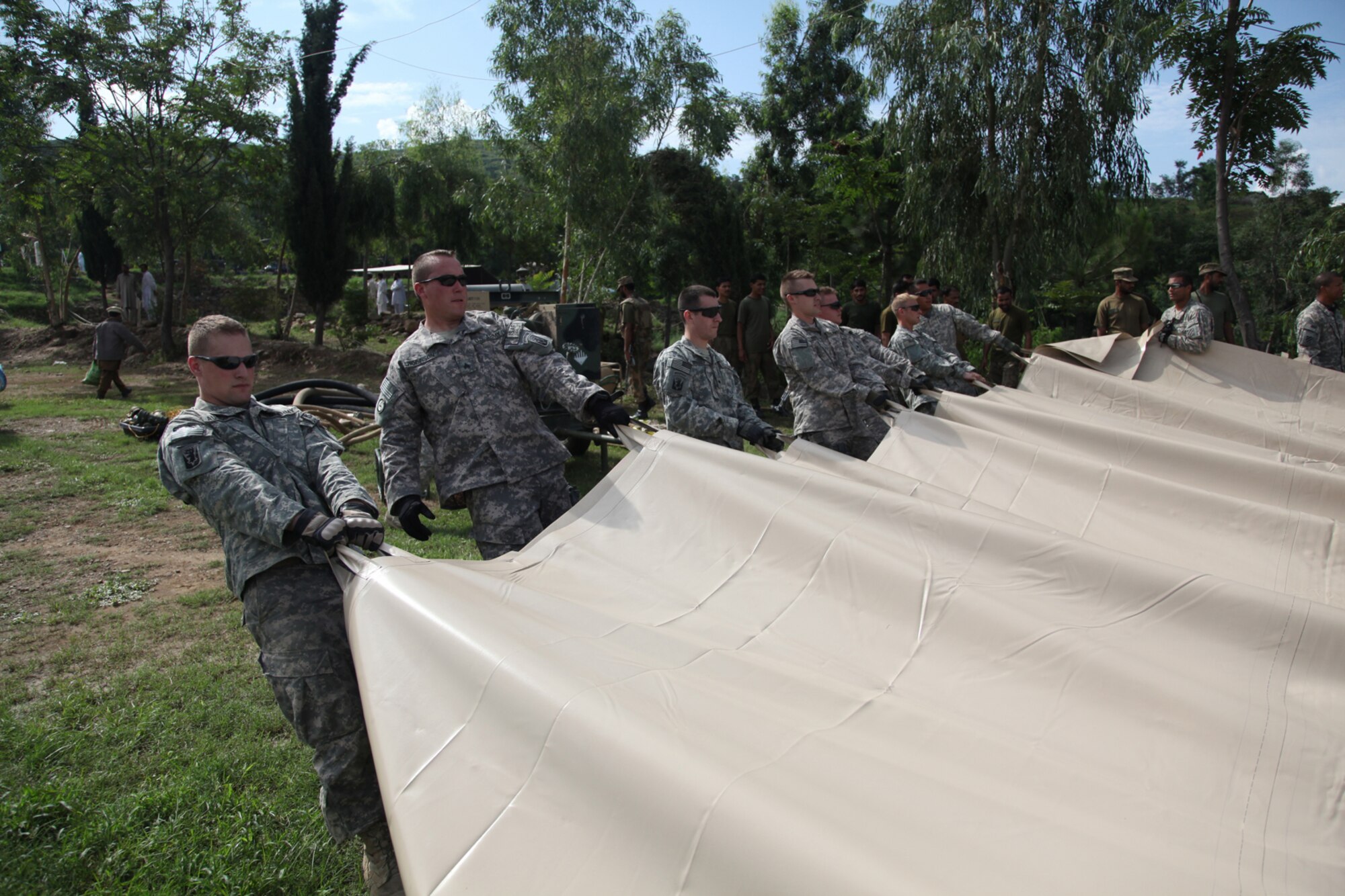 Vermont Army National Guard members from 1st Platoon, A Company, 1st Battalion, 172nd Cavalry of the 86th Infantry Brigade Combat Team along with members of E Company, 2nd Battalion, 3rd Combat Aviation Brigade pull a liner open to spread it out, before placing a fuel bladder on top as part of a forward area refueling point in Rubicon. The team worked as part of the flood relief effort in Khyber Pakhtunkhwa province, Pakistan, Aug. 10, 2010.