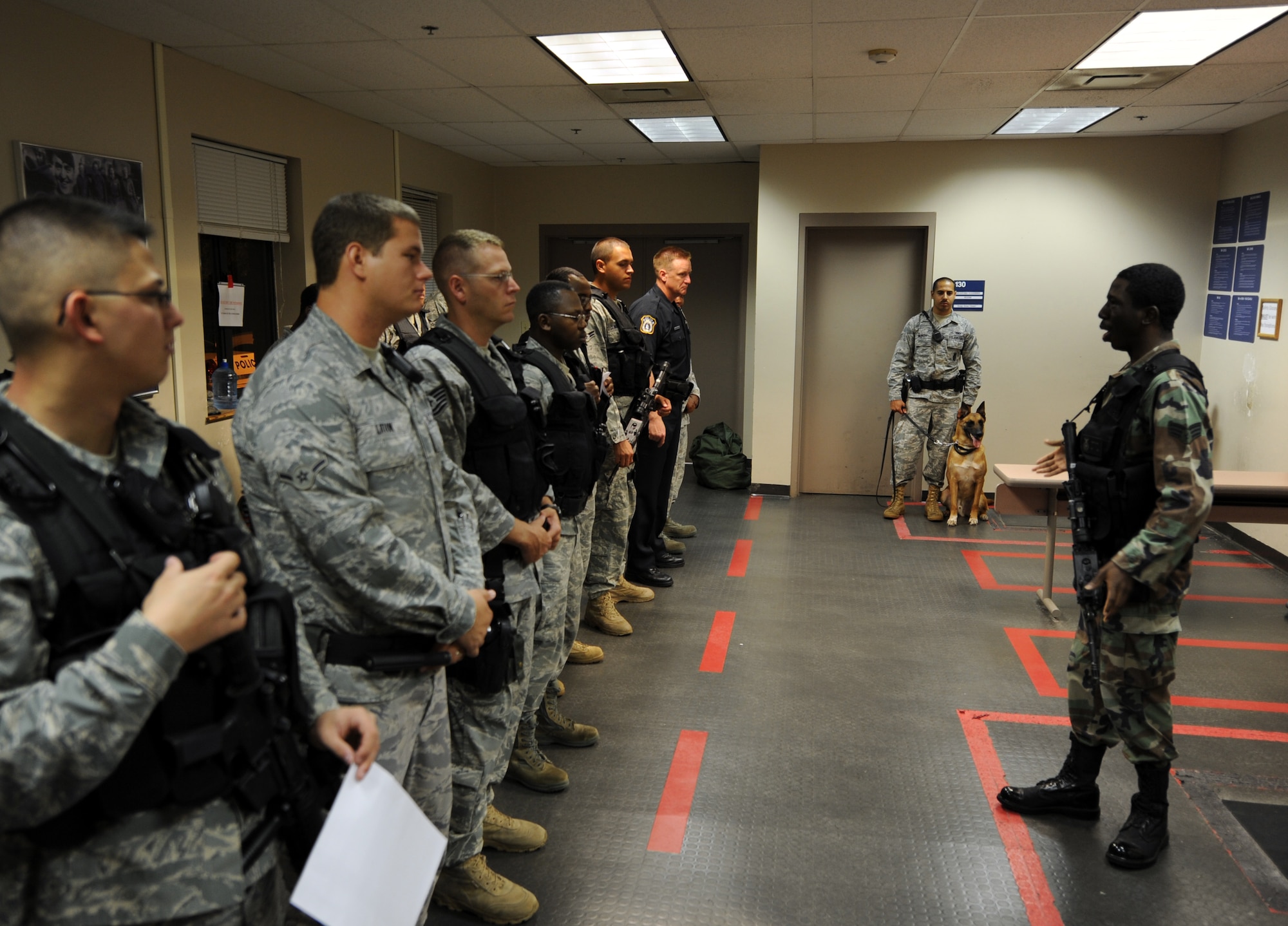 U.S. Air Force Staff Sgt. Fazel Munshi, far right, and his military working dog Arton stand by during a guard mount session at the 628th Security Forces Squadron Aug. 20, 2010, on Joint Base Charleston, S.C. Guard mount is an opportunity for the flight chief to brief safety and general information before upcoming shift changes. Having a MWD present for the meeting helps familiarize the dog to different environments. Sergeant Munshi is a dog handler with the 628th Security Forces Squadron. (U.S. Air Force photo/Senior Airman Timothy Taylor)