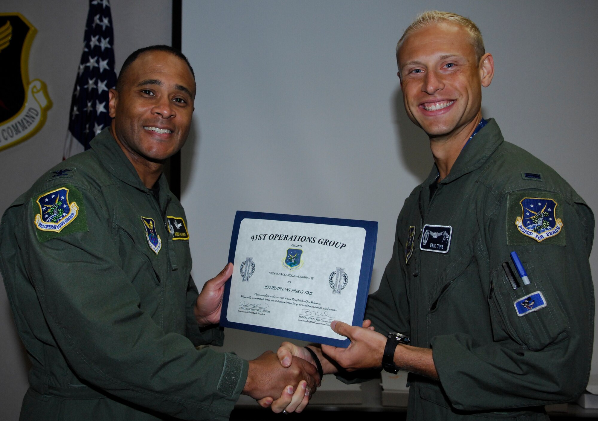 MINOT AIR FORCE BASE, N.D. – Col. Robert M. Walker, 91st Operations Group commander, gives a Crew Tour Completion Certificate to 1st Lt. Erik Tims, 742nd Missile Squadron Missile Combat Crew Commander, at the 91st Missile Wing headquarters building here Aug. 19. Lieutenant Tims took part in a once-in-a-lifetime event by pulling his last alert with his brother, 2nd Lt. Patrick Tims, 742nd MS Deputy Missile Combat Crew Commander. The alert was Patrick’s first, making the event truly unique. (U.S. Air Force photo by Tech. Sgt. Thomas Dow)