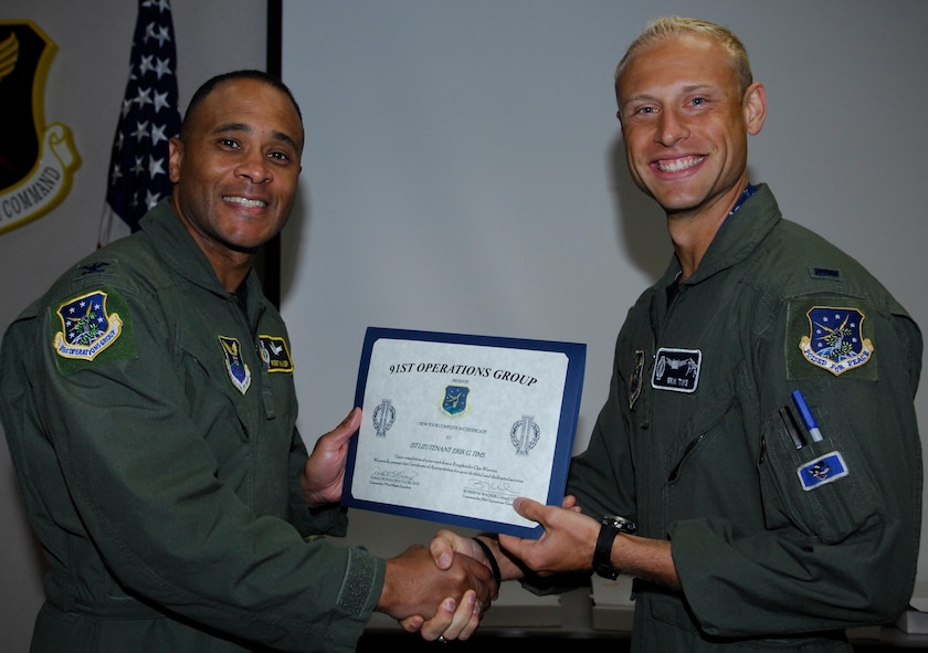 MINOT AIR FORCE BASE, N.D. – Col. Robert M. Walker, 91st Operations Group commander, gives a Crew Tour Completion Certificate to 1st Lt. Erik Tims, 742nd Missile Squadron Missile Combat Crew Commander, at the 91st Missile Wing headquarters building here Aug. 19. Lieutenant Tims took part in a once-in-a-lifetime event by pulling his last alert with his brother, 2nd Lt. Patrick Tims, 742nd MS Deputy Missile Combat Crew Commander. The alert was Patrick’s first, making the event truly unique. (U.S. Air Force photo by Tech. Sgt. Thomas Dow)