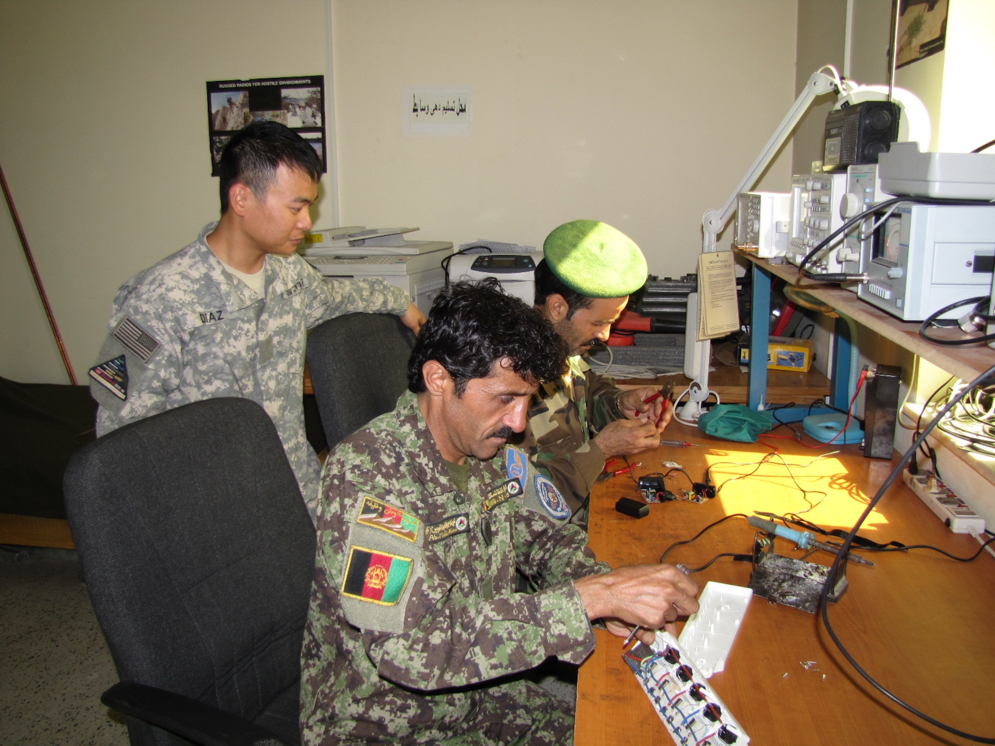 KABUL, Afghainstan - Mr. Al Diaz, a Combined Air Power Transition Force Comm mentor watches as his Afghan counterparts work on a radio on the Afghan Air Force.  (U.S. Air Force photo by Capt. Rob Leese/RELEASED).