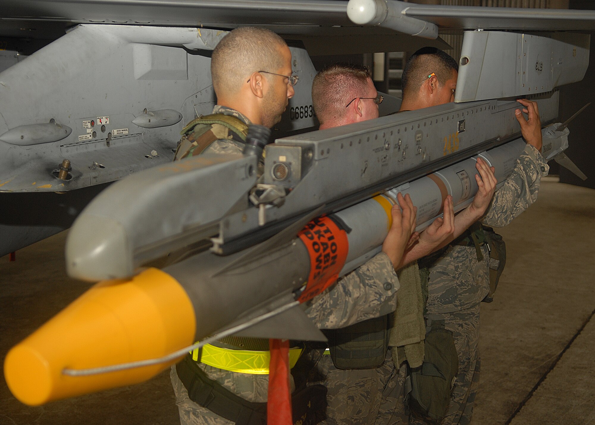 KUNSAN AIR BASE, Republic of Korea -- Weapons load crew members work together to load an AIM-120 missile to an F-16 here Aug. 25, during exercise Beverly Midnight 10-03.  Members of load crews have to precisely and promptly load missiles for flight generation. (U.S. Air Force photo/Senior Airman Ciara Wymbs)