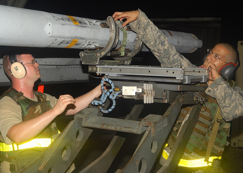 KUNSAN AIR BASE, Republic of Korea-- Staff Sgt. Thomas O’Boyle (left) and Senior Airman Jareid Juarbe, 80th Aircraft Maintenance Squadron weapons load crew members, attach a AIM-120 missile to an F-16 here Aug. 25.  Members of load crews have to precisely and promptly load missiles for flight generation during exercise Beverly Midnight 10-03.  (U.S. Air Force photo/Senior Airman Ciara Wymbs)